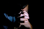 Man in prayer, head bowed, hands clasped